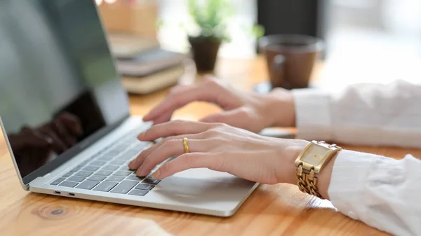 Seitenansicht einer Frau, die auf einem Laptop auf einem Holztisch tippt — Stockfoto