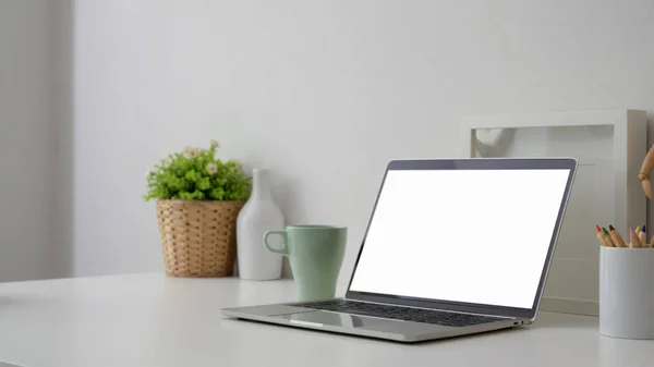 Captura recortada de lugar de trabajo con computadora portátil de pantalla en blanco, lápices de colores y decoraciones — Foto de Stock