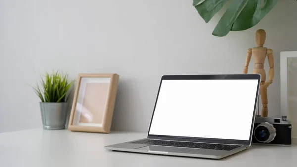 Tiro recortado de local de trabalho com laptop tela em branco, câmera e decorações — Fotografia de Stock