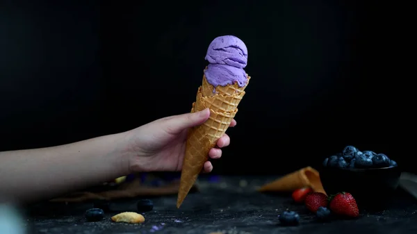 Close up view of a girl holding blueberry ice-cream cone — Stock Photo, Image