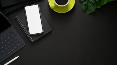 Kablosuz klavyeli iş yeri manzarası, akıllı telefon, fotokopi alanı, ofis malzemeleri ve siyah masa üzerindeki kahve fincanı. 