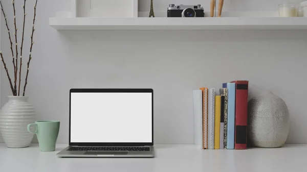 Vista cercana del lugar de trabajo con el ordenador portátil de pantalla en blanco, libros a en el escritorio blanco —  Fotos de Stock