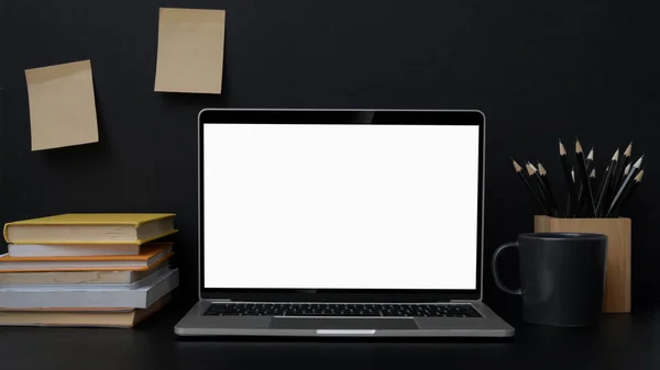 Close up widok modnego miejsca pracy z pustym ekranem laptop na czarnym stole — Zdjęcie stockowe