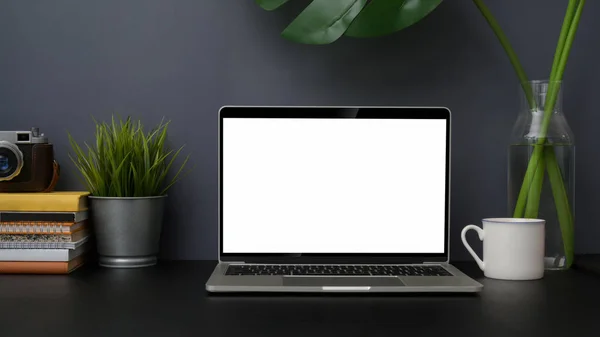 Vista da vicino del luogo di lavoro fotografo alla moda con computer portatile mock up su tavolo nero con parete grigia — Foto Stock