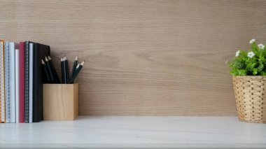 Modern kırsal duvarlı mermer masa üzerindeki basit iş yeri, fotokopi alanı, kitap, kırtasiye malzemesi ve ağaç kabı manzarasını kapat