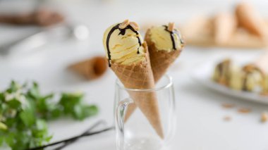 Yaz tatlısının yakın görüntüsü, üstüne çikolata sosu serpiştirilmiş vanilyalı dondurma külahları. 