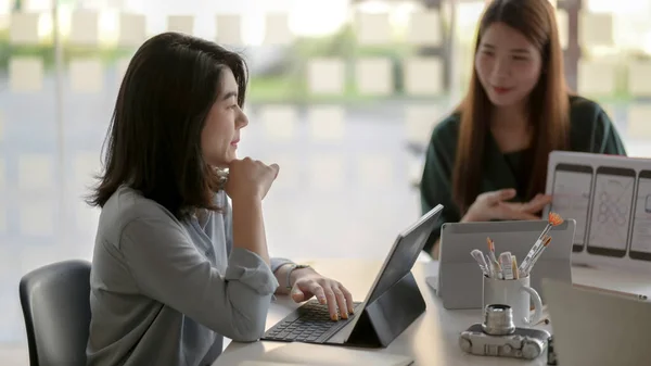 Cropped shot of female application developer presenting UI project to her headman in modern meeting room