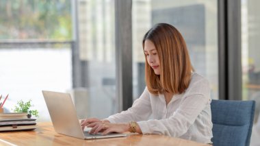 Güzel bir iş kadınının çalışma odasında rahat bir şekilde otururken çekilmiş görüntüsü.