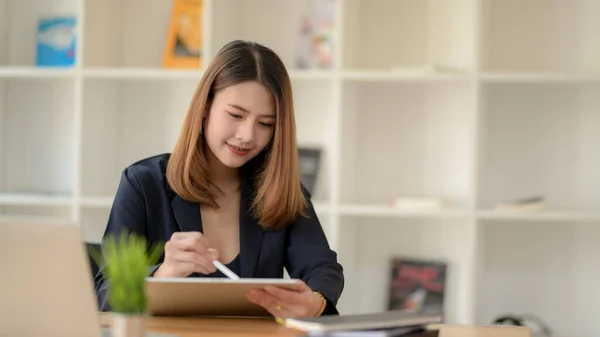 Cropped shot of businesswoman drawing on digital tablet while sitting in modern office room