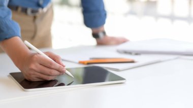 Çalışma odasında rahat bir şekilde dururken dijital tablet üzerinde çalışan erkek girişimcilere yakından bakın.