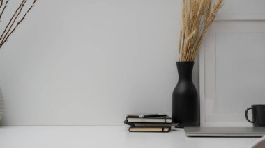 Dizüstü bilgisayar, kahve fincanı, dekorasyon ve beyaz masa üzerindeki beyaz duvar arkaplanlı kopya alanı ile en az çalışma alanı görüntüsünü kapat 