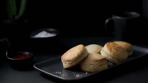Cropped shot of traditional British Scones with strawberry jam and clotted cream on black plate