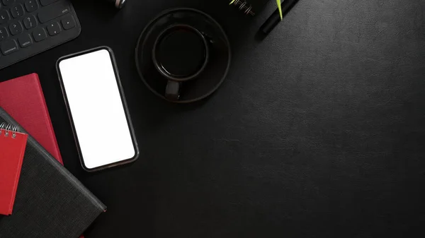 モックアップ付きダークモダンワークスペースのトップビュースマートフォン オフィス用品 コーヒーカップとブラックデスク上のコピースペース — ストック写真