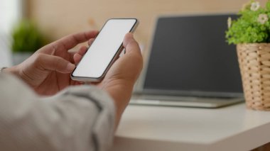 Basit bir iş yerinde işten kaytarırken boş ekran akıllı telefonuna mesaj atan serbest çalışan bir erkeğin görüntüsü.
