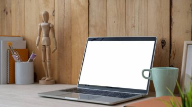Boş ekran laptop, ofis malzemeleri ve ahşap masa üzerindeki ahşap duvar arka planlı dekorasyonla çağdaş iş yerinin kırpılmış görüntüsü. 