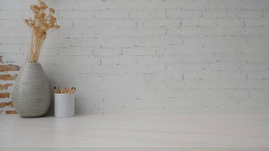 Renkli kalemler ve tuğla duvar zeminli mermer masadaki seramik vazo ile minimal kopya alanının görüntüsünü kapat