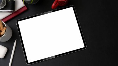 Siyah masa üzerinde tablet, stil ve diğer malzemelerle şık bir iş yeri fotoğrafı.  