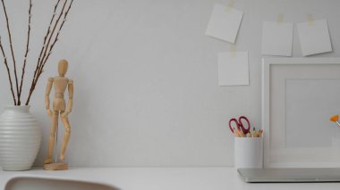 Dizüstü bilgisayar, çerçeve, boyama araçları, dekorasyonlar ve beyaz masadaki yapışkan notla en az tasarımcı çalışma alanını kapat 