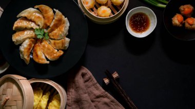 Siyah tabakta kızarmış Japon Gyoza köfteleriyle Dim sum 'un üst görüntüsü geleneksel buharlı Çin köfteleri ve siyah masada soya sosu servis ediliyor. 