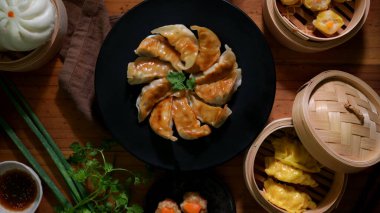 Dim sum 'un en iyi manzarası kızarmış Japon Gyoza köfteleriyle siyah tabakta, Çin mantısı ve çörekler geleneksel buharlı vapurda servis ediliyor.  