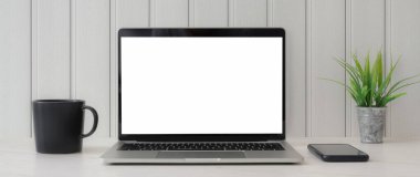 Boş ekran dizüstü bilgisayar, akıllı telefon, kahve fincanı ve beyaz tahta arka planlı ağaç tepsisiyle en az çalışma alanı görüntüsü.  