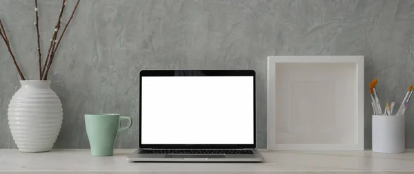 灰色のロフト壁と大理石の机の上にモックアップノートパソコン 絵画ブラシや装飾とトレンディーなワークスペースのトリミングショット — ストック写真