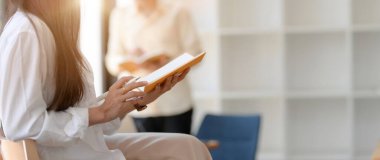 Kütüphanede tahta sandalyede otururken üniversite öğrencisinin sınava hazırlanışının yan görüntüsü.