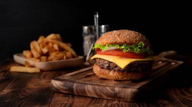 Ahşap tepside taze hamburger ve kırsal masada patates kızartması.