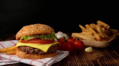 Taze sığır burger, patates kızartması ve ahşap ahşap masa malzemeleri.