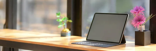 Cropped shot of portable workspace with blank screen tablet on wooden counter bar with copy space and decorations in coffee shop
