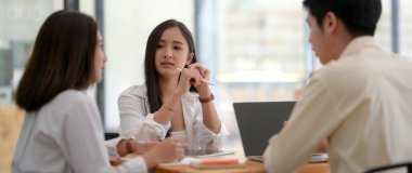 Üniversite öğrencileri grubunun tahta masada dijital cihazla beyin fırtınası yaparken çekilmiş görüntüleri. 