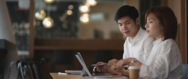 Dijital cihazla projelerinde danışmanlık yaparken birlikte çalışan iki iş adamının yan görünümü