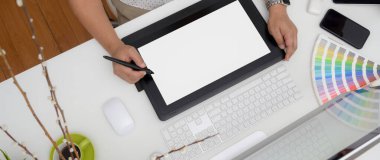 Model tablet, bilgisayar aygıtı, akıllı telefon ve beyaz masadaki renk örnekleri üzerinde çalışan tasarımcının genel görüntüsü  