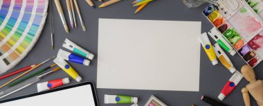 Kağıt çizimi, renk örneği, tablet ve boya araçları ile ressam çalışma alanının genel görüntüsü gri masa üzerinde