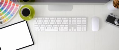 Boş ekran tableti, bilgisayar aygıtı ve tasarımcı malzemeleriyle beyaz masada grafik tasarımcı çalışma alanının genel görüntüsü 