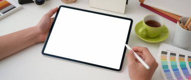 Boş ekran tabletine çizim yapan genç bir erkek grafik tasarımcısının en az çalışma alanı üzerine stilus kalemle kırpılmış görüntüsü