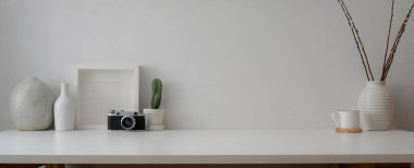 Kamera, dekorasyon ve beyaz duvarlı beyaz masanın üzerindeki küçük çalışma alanının kırpılmış görüntüsü 