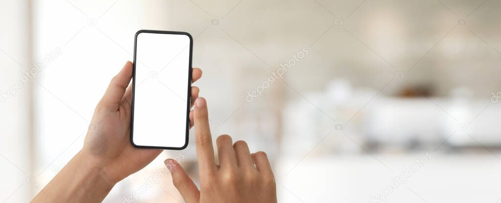 Cropped shot of a man touching on blank screen smartphone in blurred glass partition office room background