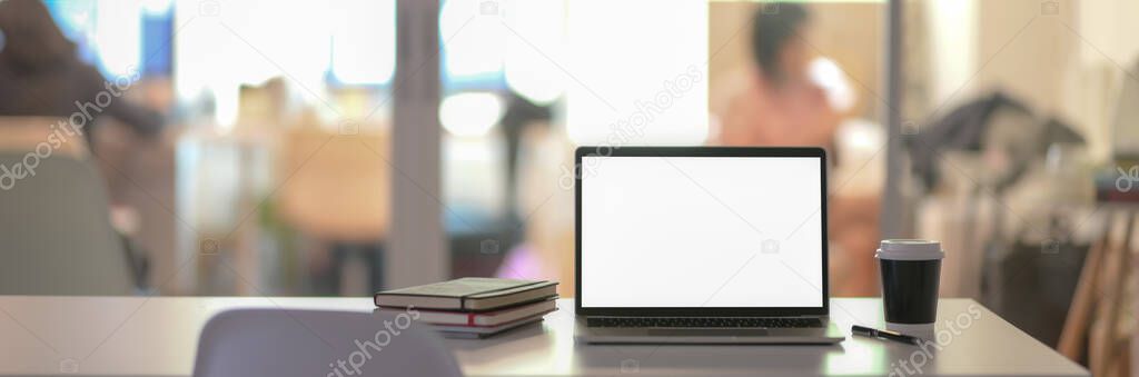 Cropped shot of office desk with blank screen laptop and supplies on white table in glass partition room