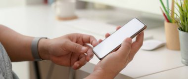 Ofis masasında dinlenirken elinde akıllı telefon olan bir adamın yakın görüntüsü. 