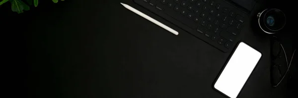 ブラックテーブルの上にモックアップスマートフォン タブレット 黒の色の供給と暗い概念の職場のトップビュー — ストック写真
