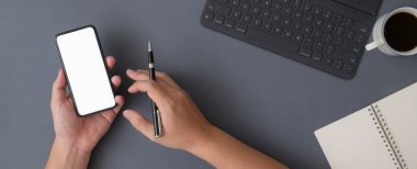 Gri masadaki dijital tablet ve kırtasiyeyle çalışırken akıllı telefon kullanan işadamının genel görüntüsü