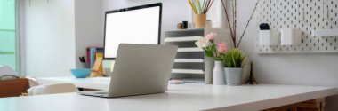 Boş ekran bilgisayarı, ofis malzemeleri, dekorasyonlar ve beyaz masadaki dizüstü bilgisayarla basit ofis masasının kırpılmış görüntüsü.  