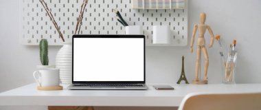Beyaz masadaki boş ekran laptop, dekorasyon ve malzemeler ile ev ofisinin görüntüsünü kapat  