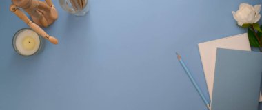 Günlük defterleri, dekorasyonları ve açık mavi masadaki alanı kopyalayan yaratıcı çalışma alanının üst görünümü 