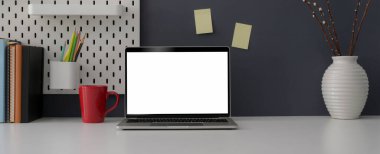 Boş ekran laptop, kupa, ofis malzemeleri, dekorasyon ve beyaz masa üzerindeki kopyalama alanı ile şık ofis masasının görünümünü kapat  