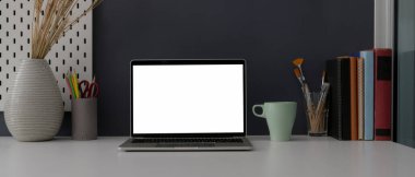 Beyaz masa arkasındaki ofis masasını boş ekran laptop, dekorasyon ve malzemelerle kapat 
