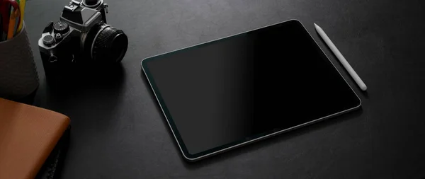 黒いテーブルの背景にデジタルタブレット カメラなどの電源で暗い現代のワークスペースの切り取られたショット — ストック写真