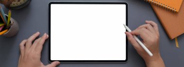 Stylus ve ofis masasındaki diğer malzemelerle birlikte tablet üzerinde çalışan kadın girişimcinin genel görüntüsü.  