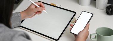 Kadın tasarımcının yatay model akıllı telefon hakkında bilgi ararken maket tabletle çalışırken çekilmiş görüntüsü 